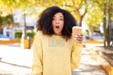 Téléchargez les photos : Jolie afro femme noire se sentant extrêmement choqué et surpris. concept de café à emporter - en image libre de droit