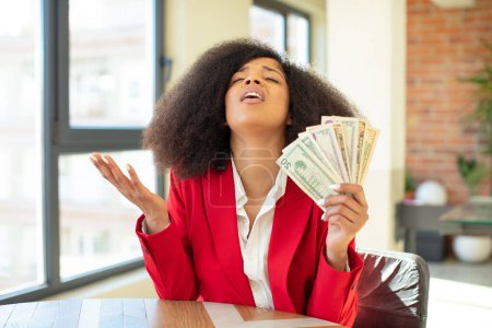 Foto de Mujer negra bastante afro gritando con las manos arriba en el aire. concepto de billetes en dólares - Imagen libre de derechos