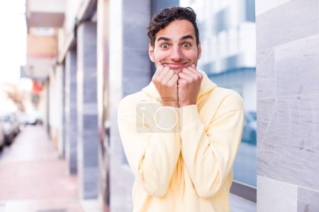Photo for Young hispanic man happy and excited, surprised and amazed, giggling with a cute expression - Royalty Free Image