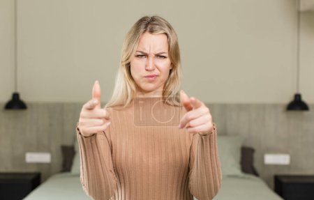 Photo for Young pretty woman pointing forward at camera with both fingers and angry expression, telling you to do your duty. bed concept - Royalty Free Image