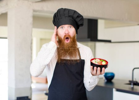Photo for Red hair man feeling extremely shocked and surprised with a ramen bowl. chef concept - Royalty Free Image