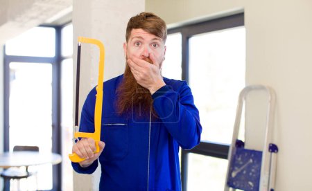 Photo for Red hair man covering mouth with a hand and shocked or surprised expression repairing home. handyman concept - Royalty Free Image