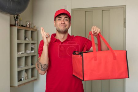 Photo for Young handsome man crossing fingers and hoping for good luck. pizza delivery concept - Royalty Free Image