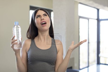 Téléchargez les photos : Jolie jeune femme criant les mains en l'air. concept de bouteille d'eau - en image libre de droit