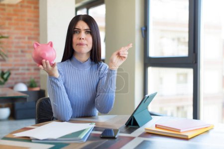 Photo for Pretty young woman crossing fingers and hoping for good luck. piggy bank concept - Royalty Free Image