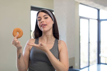 Photo for Pretty young woman smiling cheerfully, feeling happy and showing a concept. donut concept - Royalty Free Image
