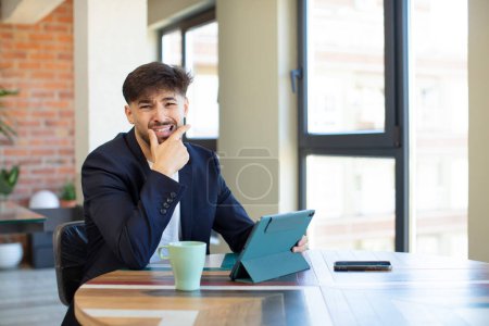 Photo for Young handsome man with mouth and eyes wide open and hand on chin. touch screen pad concept - Royalty Free Image