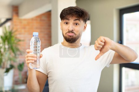 Photo for Young handsome man feeling cross,showing thumbs down. water bottle concept - Royalty Free Image