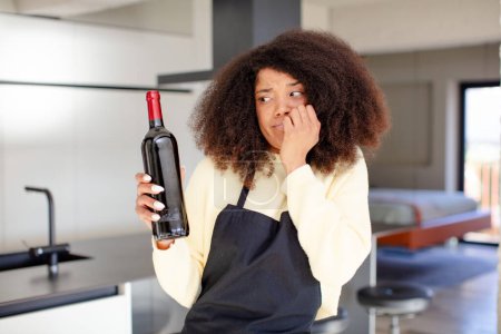 Foto de Mujer negra bastante afro sentirse asustado, preocupado o enojado y mirando a un lado. concepto botella de vino - Imagen libre de derechos