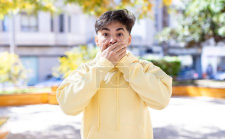 Photo for Young handsome man covering mouth with hands with a shocked, surprised expression, keeping a secret or saying oops - Royalty Free Image