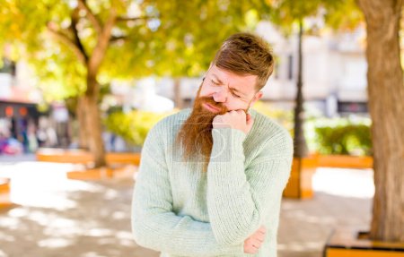 Téléchargez les photos : Cheveux roux barbu homme se sentant triste et stressé, bouleversé à cause d'une mauvaise surprise, avec un regard négatif, anxieux - en image libre de droit