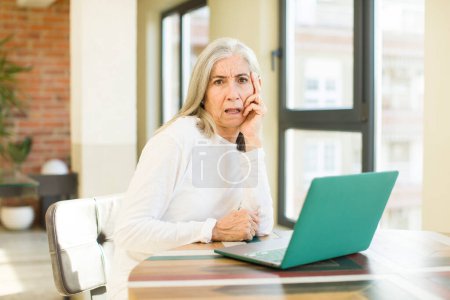 Téléchargez les photos : Senior jolie femme se sentant ennuyé, frustré et somnolent après un fatigant avec un ordinateur portable - en image libre de droit