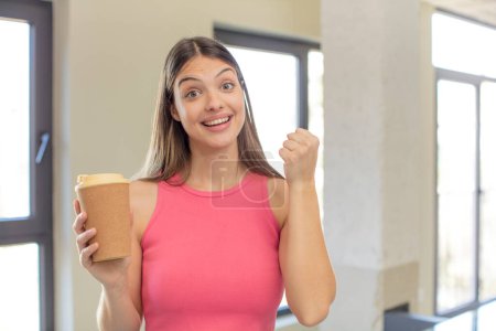 Téléchargez les photos : Jeune jolie femme se sentant choquée, riant et célébrant le succès. concept de café à emporter - en image libre de droit