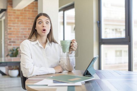 Photo for Young pretty woman feeling extremely shocked and surprised. telecommuting concept - Royalty Free Image