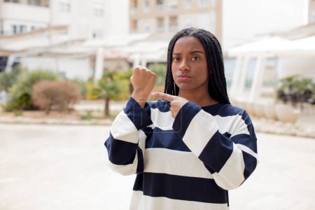 Photo for Afro pretty black woman looking impatient and angry, pointing at watch, asking for punctuality, wants to be on time - Royalty Free Image