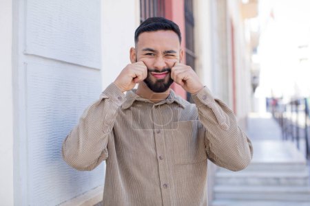 Photo for Young handsome man smiling and pointing to own fake smile - Royalty Free Image