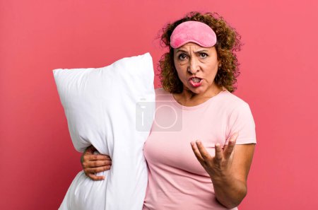 Photo for Pretty middle age woman looking angry, annoyed and frustrated wearing pajamas night wear and a pillow - Royalty Free Image