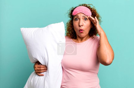 Foto de Mujer de mediana edad que parece sorprendida, dándose cuenta de un nuevo pensamiento, idea o concepto de usar pijamas ropa de noche y una almohada - Imagen libre de derechos