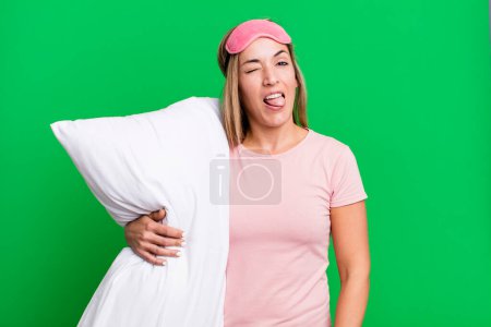 Foto de Bonita mujer rubia con actitud alegre y rebelde, bromeando y sacando la lengua. concepto de pijama o ropa de dormir - Imagen libre de derechos