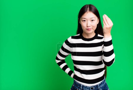Foto de Bonita mujer asiática haciendo capice o dinero gesto, diciéndote que pagar - Imagen libre de derechos