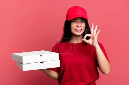 Foto de Mujer bonita hispana sintiéndose feliz, mostrando aprobación con gesto bien. entrega concepto de pizza - Imagen libre de derechos