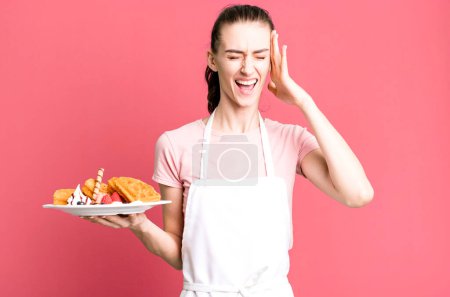Photo for Young pretty woman looking unhappy and stressed, suicide gesture making gun sign. waffles concept - Royalty Free Image