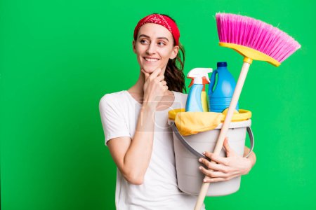 Téléchargez les photos : Young pretty woman smiling with a happy, confident expression with hand on chin. housekeeper concept - en image libre de droit