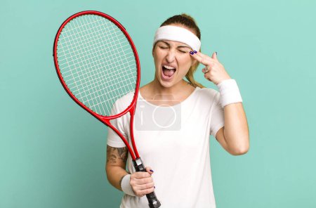 Foto de Joven bonita mujer buscando infeliz y estresado, gesto suicida haciendo señal de arma. concepto de tenis - Imagen libre de derechos