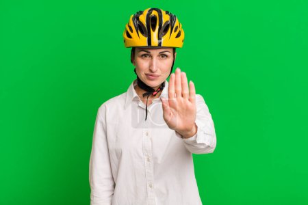 Photo for Young pretty woman looking serious showing open palm making stop gesture. business and bike concept - Royalty Free Image