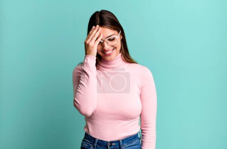 Photo for Pretty young adult woman laughing and slapping forehead like saying doh! I forgot or that was a stupid mistake - Royalty Free Image