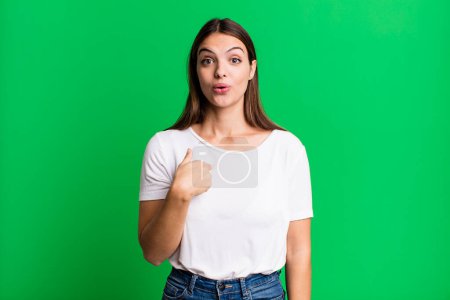 Téléchargez les photos : Pretty young adult woman looking happy, proud and surprised, cheerfully pointing to self, feeling confident and lofty - en image libre de droit