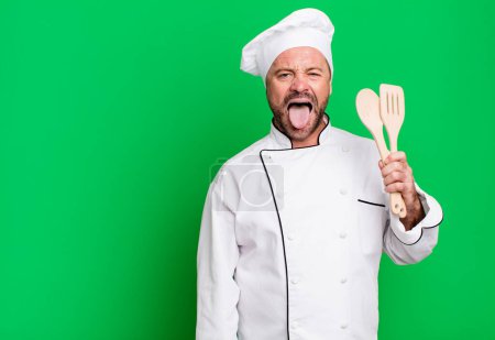 Photo for Middle age man feeling disgusted and irritated and tongue out. chef and tools concept - Royalty Free Image
