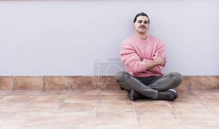 Téléchargez les photos : Jeune homme beau assis sur le sol avec un copyspace - en image libre de droit