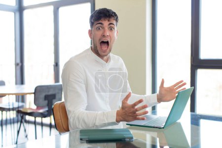 Photo for Young handsome man feeling happy and astonished at something unbelievable. working at home concept - Royalty Free Image