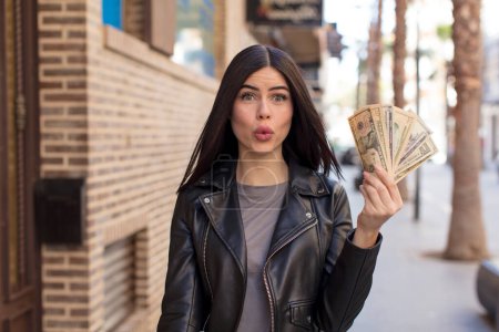Photo for Pretty young woman feeling extremely shocked and surprised. dollar banknotes concept - Royalty Free Image