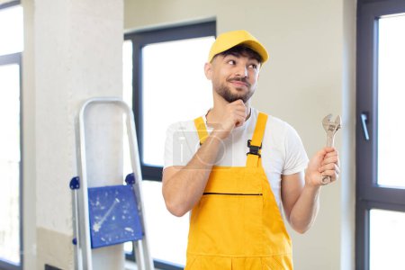 Photo for Young handsome man smiling with a happy, confident expression with hand on chin. handyman concept - Royalty Free Image