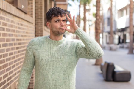 Photo for Young handsome man looking serious and displeased with both fingers crossed up front in rejection, asking for silence - Royalty Free Image