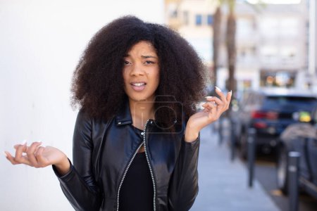 Photo for African american pretty woman looking puzzled, confused and stressed, wondering between different options, feeling uncertain - Royalty Free Image