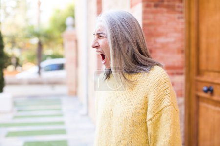 Foto de Jubilado bastante blanco pelo mujer gritando agresivamente, mirando muy enojado, frustrado, indignado o molesto, gritando no - Imagen libre de derechos