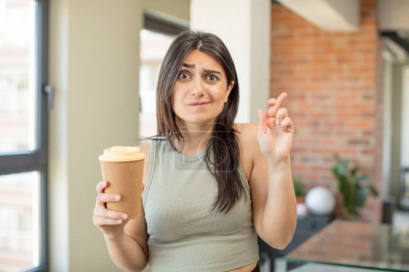 Téléchargez les photos : Jeune femme croisant les doigts et espérant bonne chance. emporter café - en image libre de droit