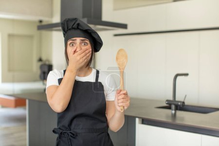 Photo for Young woman covering mouth with a hand and shocked or surprised expression. chef concept - Royalty Free Image