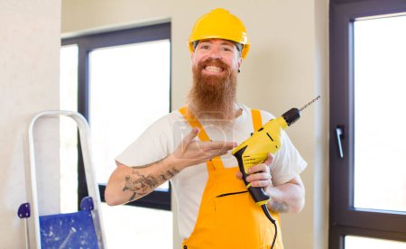 Téléchargez les photos : Homme aux cheveux roux souriant joyeusement, se sentant heureux et montrant un concept de réparation de la maison. concept bricoleur - en image libre de droit