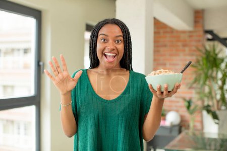 Foto de Negro afro mujer sintiéndose feliz y asombrado por algo increíble. concepto de plato de desayuno - Imagen libre de derechos