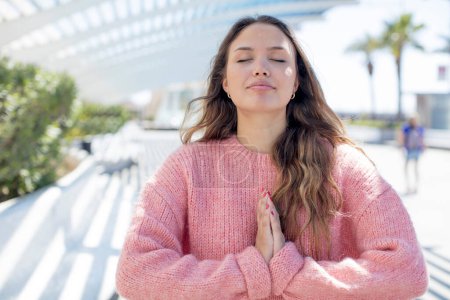 Foto de Mujer hispana bonita sintiéndose preocupada, esperanzada y religiosa, orando fielmente con las palmas presionadas, rogando perdón - Imagen libre de derechos