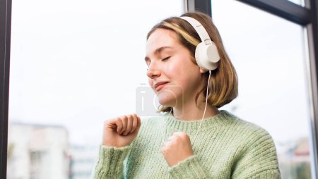 Foto de Mujer joven y bonita escuchando música con auriculares. casa de diseño de interiores - Imagen libre de derechos
