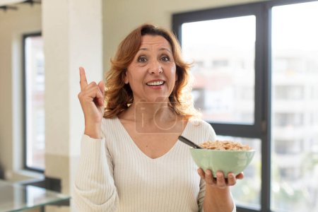 Foto de Mujer bonita de mediana edad sintiéndose como un genio feliz y emocionado después de darse cuenta de una idea. concepto de plato de desayuno - Imagen libre de derechos