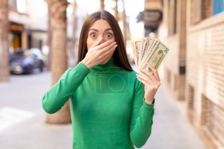 Photo for Covering mouth with a hand and shocked or surprised expression. dollar banknotes concept - Royalty Free Image