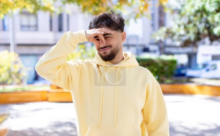 Photo for Young handsome man feeling disgusted, holding nose to avoid smelling a foul and unpleasant stench - Royalty Free Image