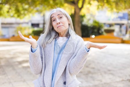 Téléchargez les photos : Senior retraité jolie femme aux cheveux blancs se sentant perplexe et confus, doutant, pesant ou choisissant différentes options - en image libre de droit