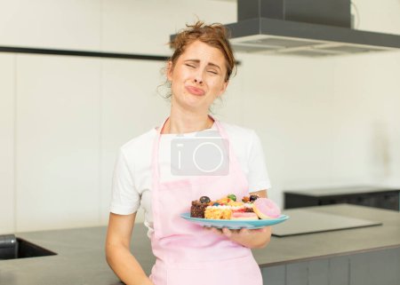 Téléchargez les photos : Young pretty woman feeling sad and whiney with an unhappy look and crying. home made cakes concept - en image libre de droit